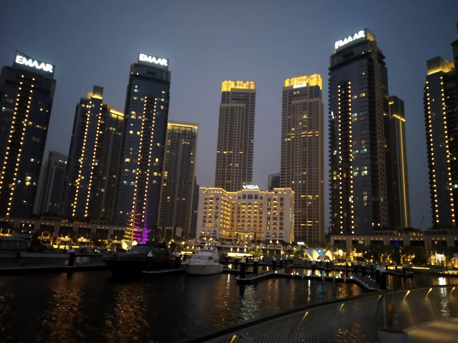 Towers of Dubai Creek Harbour lit up over the marina at dusk